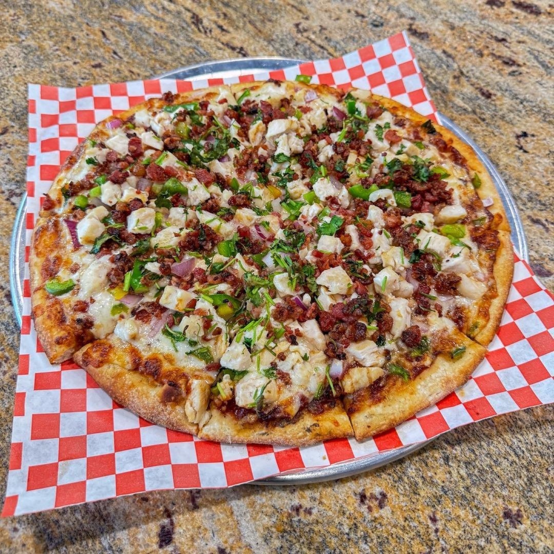 Fresh specialty pizza on red checker paper